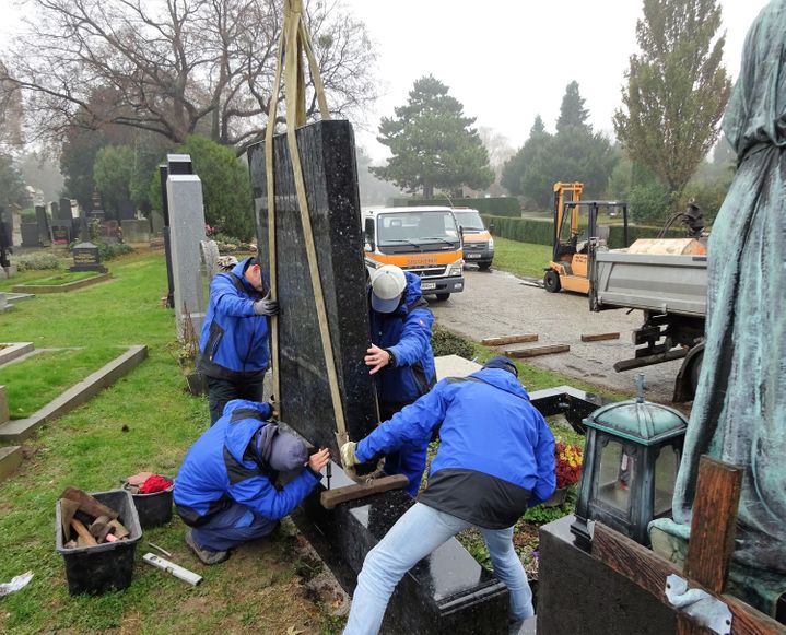 Grabstein wird von vier Fachkräften verzapft für Kippsicherheit des Grabsteins in Wien